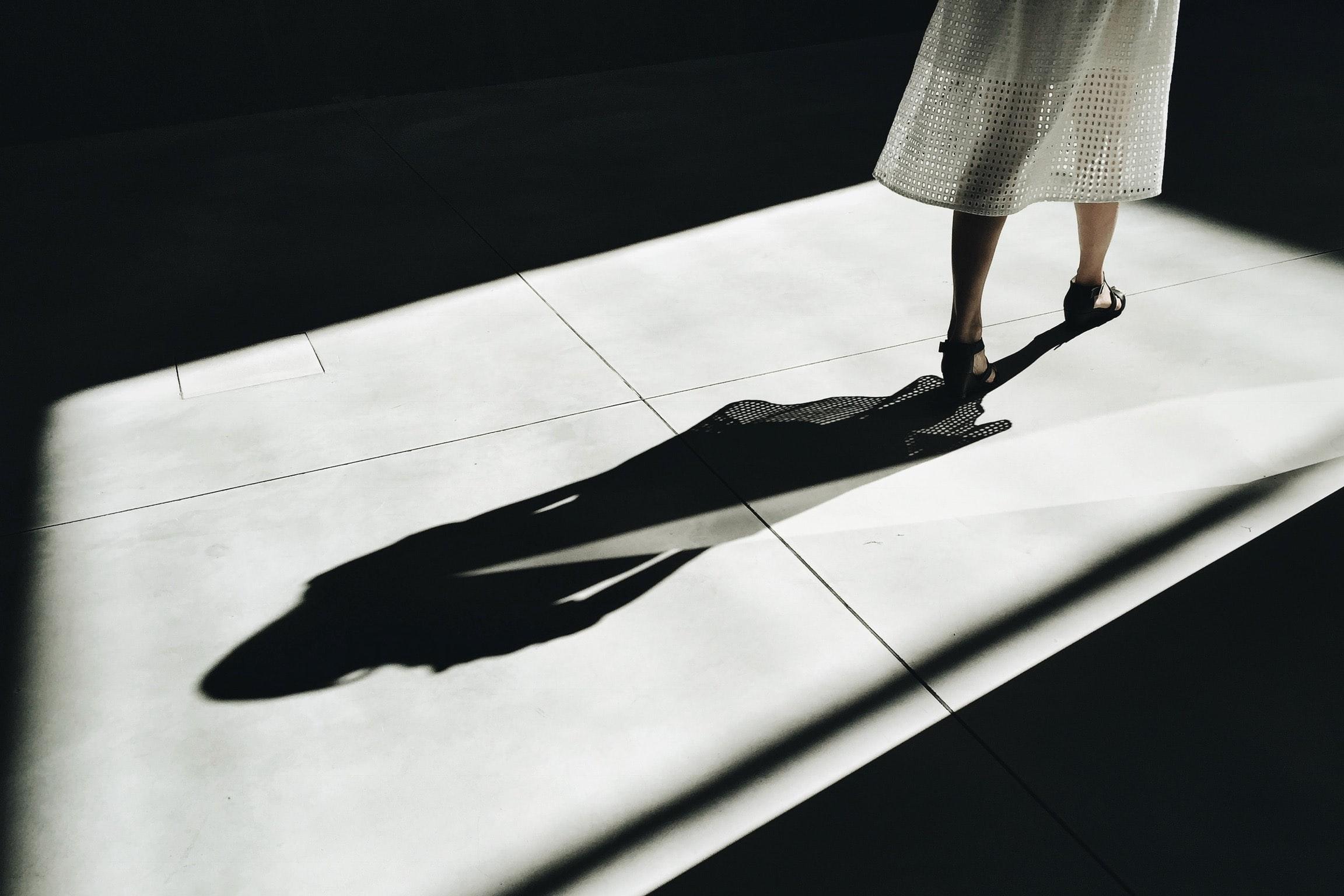 A woman being followed by her shadow.
